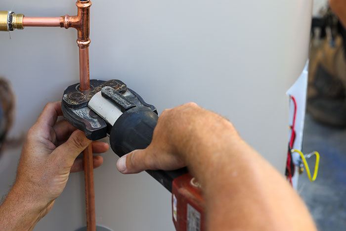 Plumber compressing copper pipes on a hot water system in Caloundra